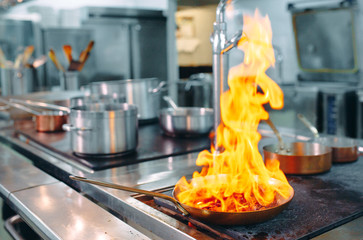 Obraz premium Modern kitchen. Cooks prepare meals on the stove in the kitchen of the restaurant or hotel. The fire in the kitchen.
