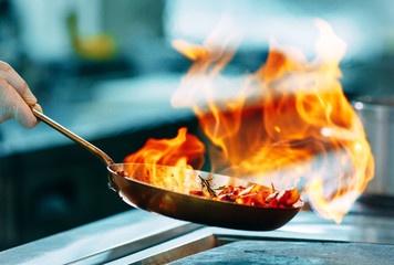 Moderne keuken. Koks bereiden maaltijden op het fornuis in de keuken van het restaurant of hotel. Het vuur in de keuken.