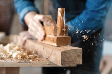 carpenter working with plane on wooden background.