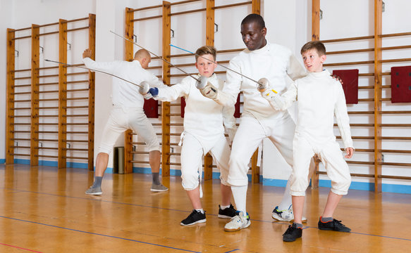 Fencing instructor with young fencers in training room