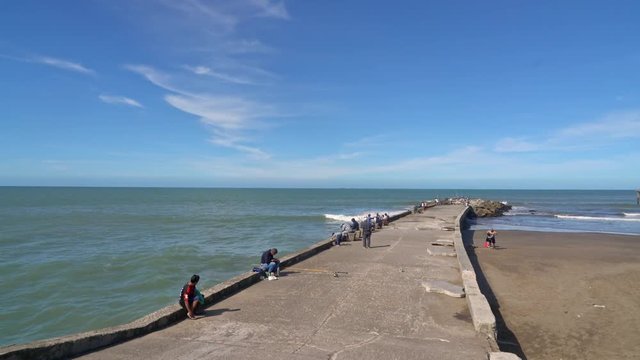 Locals fishing on a pier near Playa Punta Iglesia La Perla and the beach