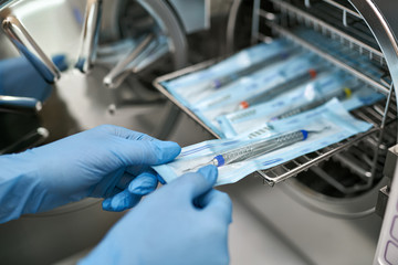 Dentist is taking dental probe from sterilize machine - obrazy, fototapety, plakaty