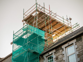 Scaffolding set on an old house to repair chimney. Construction business concept and technology.