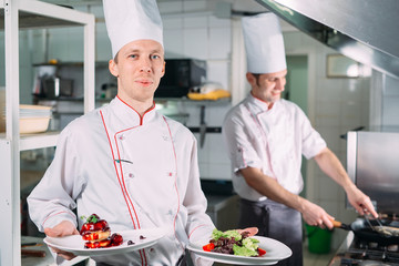 Portrait of the Chef in the kitchen of the restaurant with a ready-made dish Foie Gras.