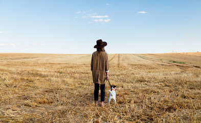 Naklejka na ściany i meble Woman in hat with dog on field