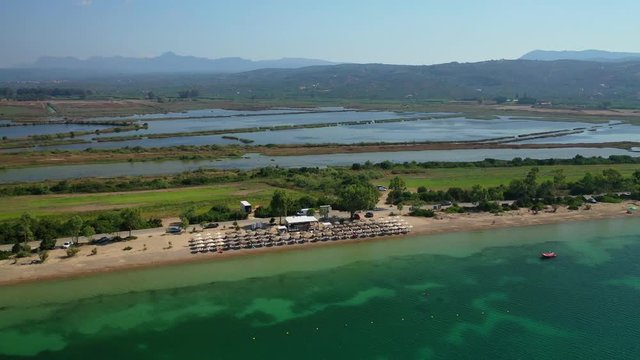 Aerial drone video of iconic secluded sandy beach with emerald sea in island of Sfaktiria next to bay and famous beach of Divari (chrysi akti), Messinia, Gialova, Peloponnese, Greece