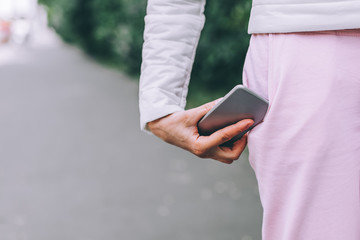 Close up of woman's hand catches smartphone falling out of pants pocket.