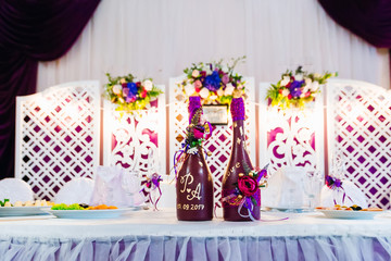 inscriptions and flowers on bottles of champagne. Wedding table