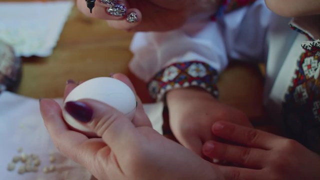 Close view of painting easter egg by mother with daughter
