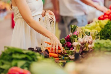  Vrouwelijke handen zetten groenten en fruit in een katoenen zak op de voedselmarkt. Herbruikbare eco-tas om te winkelen. Geen afvalconcept. © igishevamaria