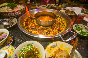 Sichuan Hot Pot in China a boiling spicy sauce and a table full of ingredients such as beef , fish...