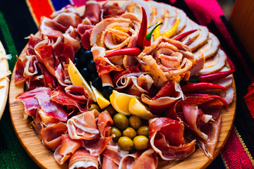 top view on a wooden plate with slices of bacon, ham and decorat