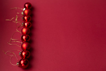 Red Christmas tree decorative toy balls on red celebratory Christmas background laid out in vertical line. New Year's holidays. Christmas holidays