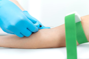 a nurse in the clinic inserts a catheter into a vein for blood testing for a young girl
