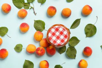Jar of apricots jam and fresh apricots on a blue background, top view	
