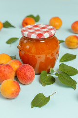 Jar of apricots jam and fresh apricots on a blue background	