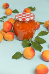Jar of apricots jam and fresh apricots on a blue background	