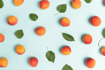 Apricots on a blue background, the flat lay image of ripe apricots and leaves	