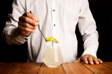 Expert bartender making a delicious cocktail on a wooden bar counter. close up shot.
