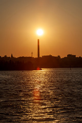 Obraz premium Setting sun over smokestack at decommissioned New Bedford Gas and Edison Light Complex