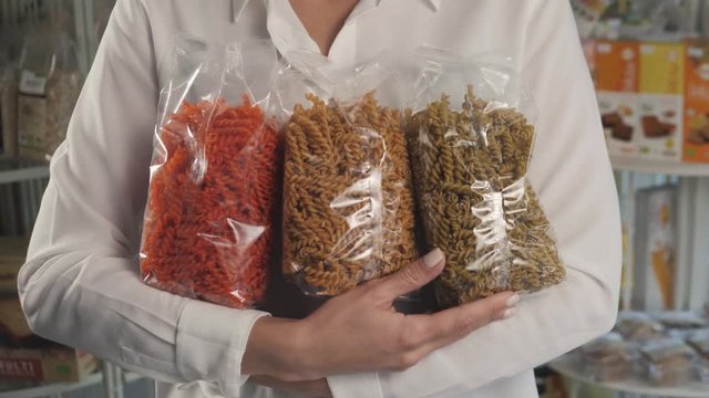 woman chooses pasta in the store, girl hold colorful pack spaghetti, bio eco italian gourmet