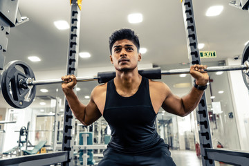 Man at the gym. Execute exercise squatting with weight, in gym