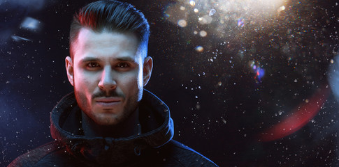 Muscular model young man with beard in hoody on dark magic background. Fashion portrait of brutal strong guy with modern trendy hairstyle and brown eyes.