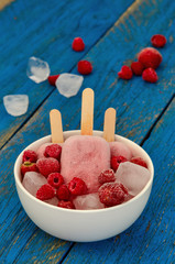 Strawberry and raspberry ice cream popsicles in white bowls