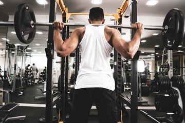 Fototapeta premium Man at the gym. Execute exercise squatting with weight, in gym