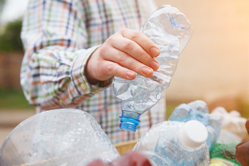 waste management, man's hand throwing clear transparent recyclable plastic bottle in garbage bin