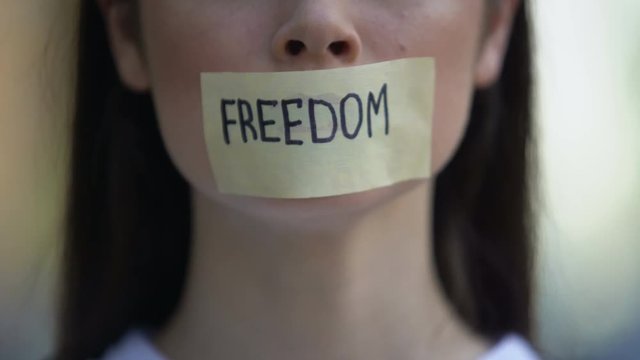 Freedom word on female taped mouth, protest against sexual harassment, concept