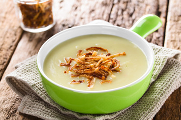 Fresh homemade cream of potato soup in green bowl garnished with crispy onion strings (Selective Focus, Focus one third into the bowl)