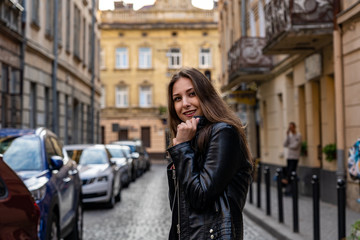 Young woman in black leather jacket is happy smiles on the street of Lviv city. Portrait photography