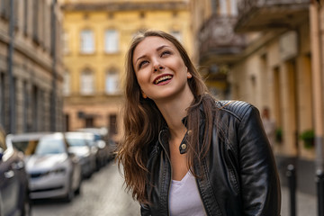 Fototapeta premium Happy young woman on the street of old city smiles and looks up