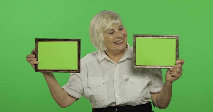 An elderly woman holding two frames with green image. Grandmother. Chroma key