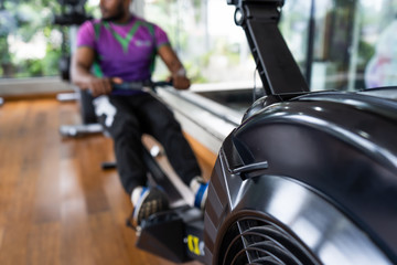 Athlete makes low cable pulley row seated in gym. Close back view