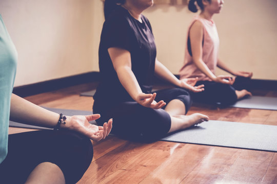 Group of young healthy Asian women practicing yoga beginner  lesson, lotus pose with instructor in home studio, wellness and fitness lifestyle concept