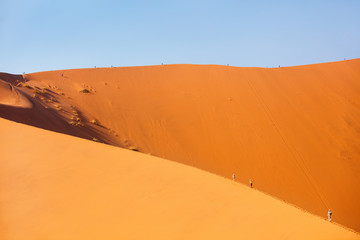 Fototapeta na wymiar Family climbing up red sand dune
