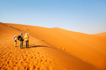 Obraz premium Family climbing up red sand dune