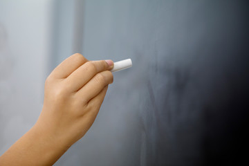 Little girl hand writing on the empty blackboard