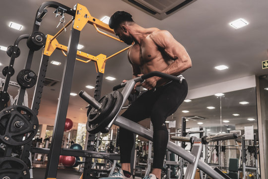 Muscular men exercising with weights. He is performing T bar rows for back muscle / Bodybuilder in the gym - Powered by Adobe