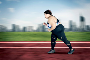 Obraz premium Obese woman sprinting exercises on the track