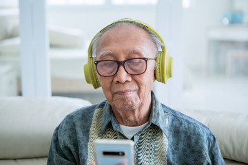 Old man enjoying music with a phone