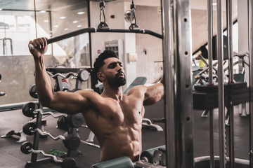 Fit man on lat pulldown machine at the health club. Work out on Pulldown Weight Machine