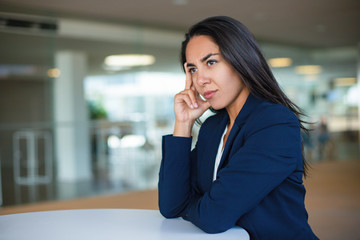 Thoughtful young businesswoman. Beautiful pensive woman in formal wear sitting at table and looking away. Emotion concept