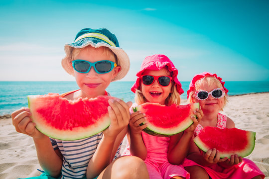 happy cute kids eating watermelon at beach