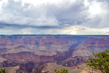 Landscape view of a Cliff in the Grand Canyon National Park, South Rim, with heavy gray clouds over it and some sunny rays