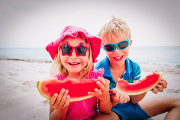 happy cute boy and girl eating watermelon at beach