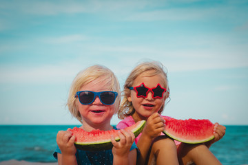 happy cute little girls eating watermelon at beach