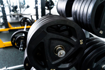 Modern light gym. Sports equipment in gym. Barbells of different weight on rack.